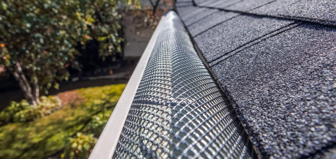 Gutter installer measuring a roofline from a ladder